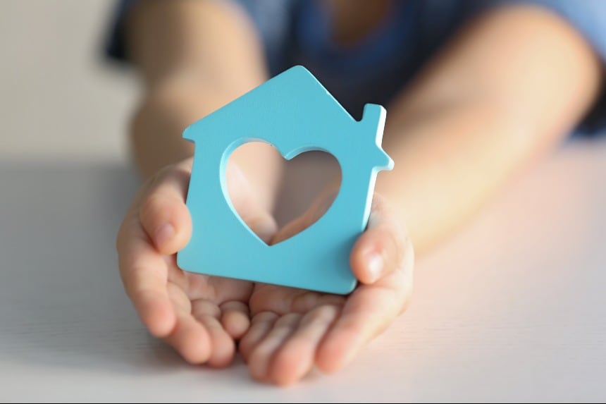 blue house with heart in the middle in hands